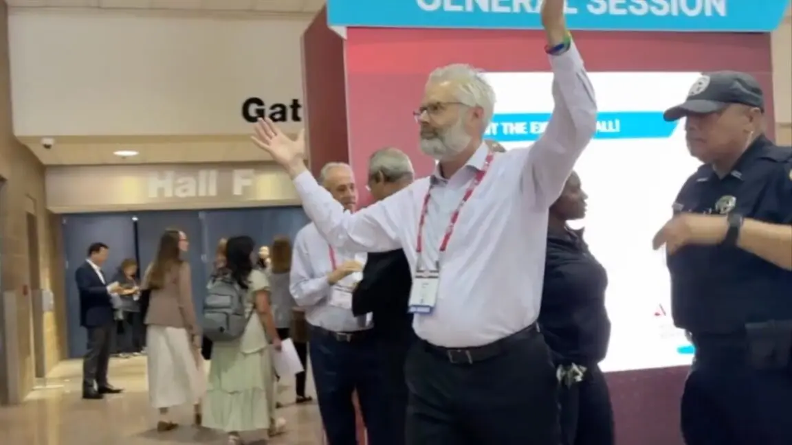 Police escort Dr. Steven Kahn out of a medical conference in New Orleans for handling out copies